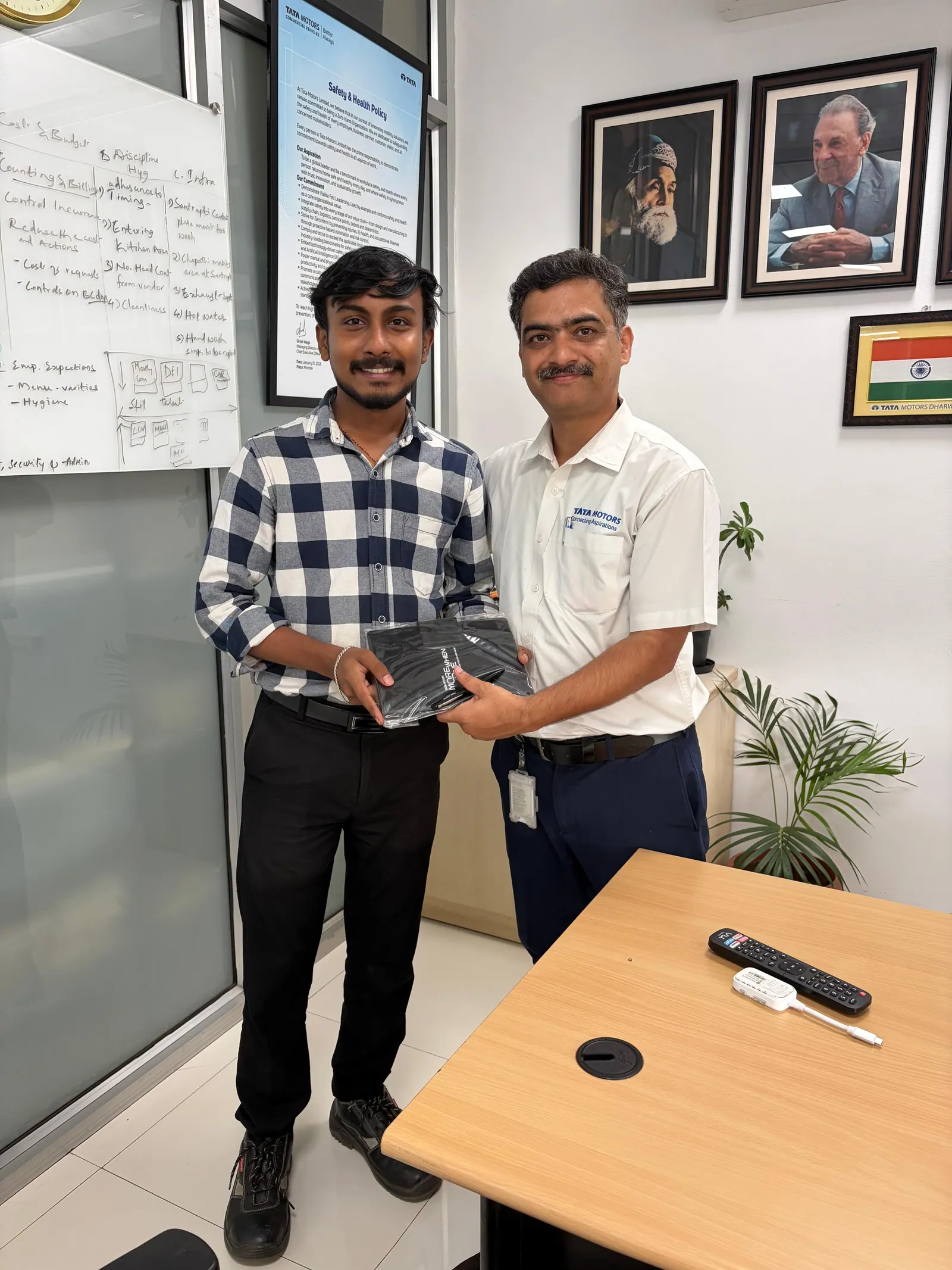 Prathamesh Halale receiving a gift from a Tata Motors colleague in an office at Tata Motors, Dharwad